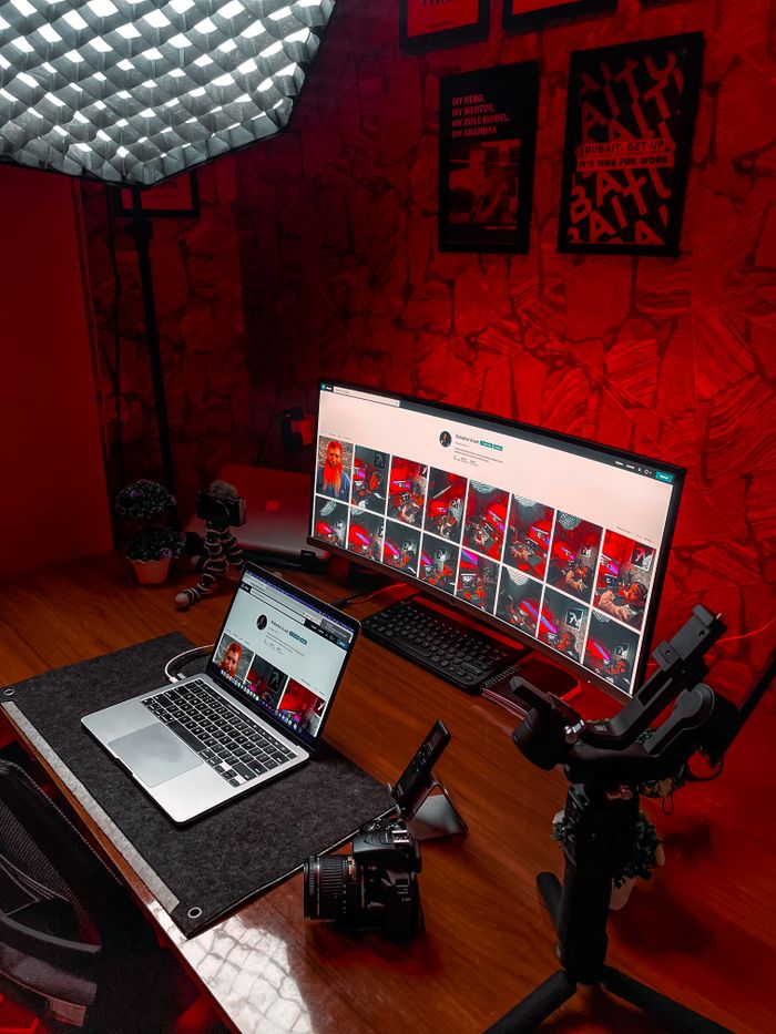 services-bg Stylish video editing setup featuring laptop and ultrawide monitor with striking red lighting.