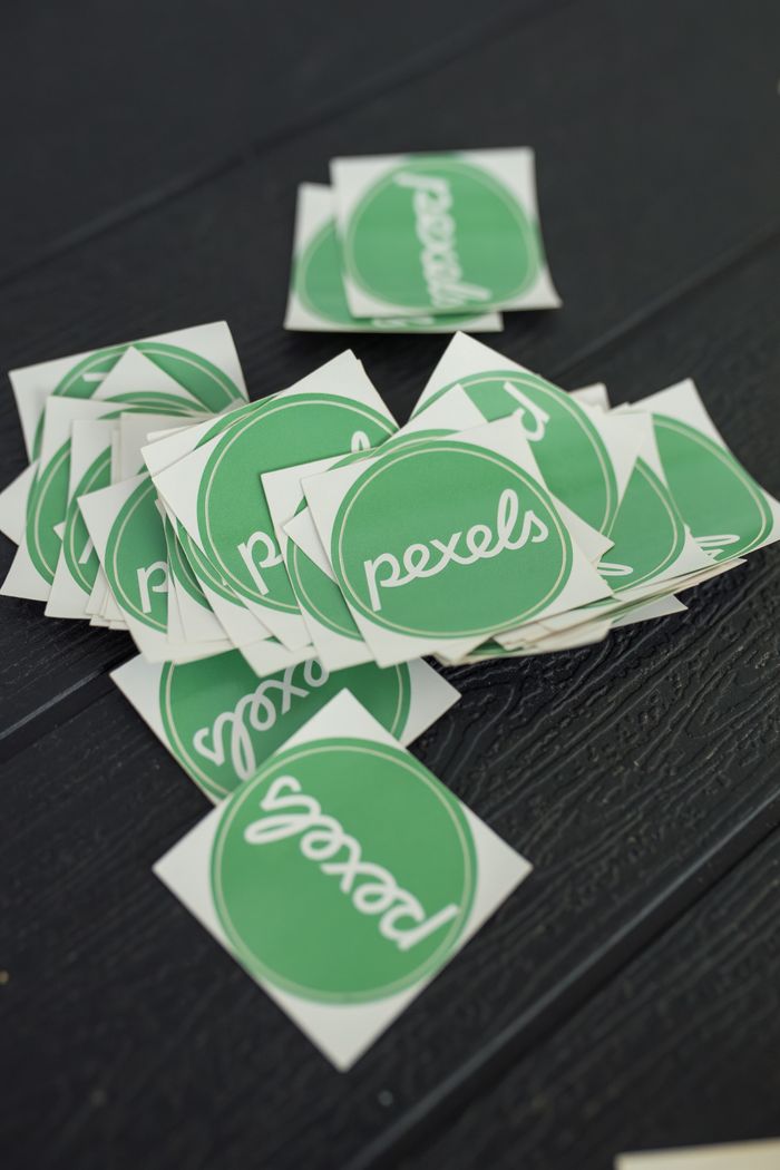 about-bg A scattered pile of green Pexels logo stickers on a textured dark surface, perfect for branding visuals.