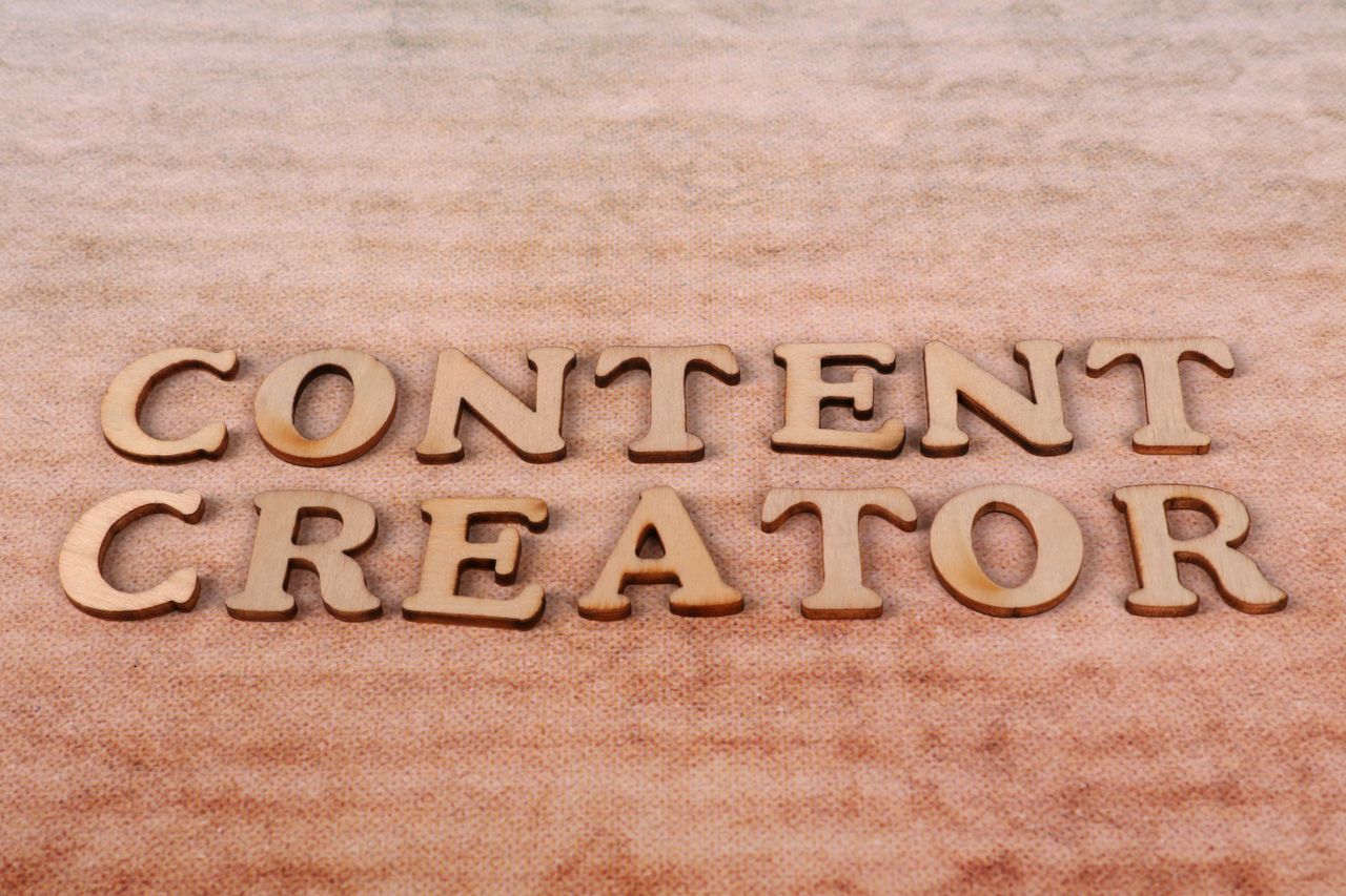 services-02 Wooden letters spelling 'Content Creator' arranged on a textured fabric background.
